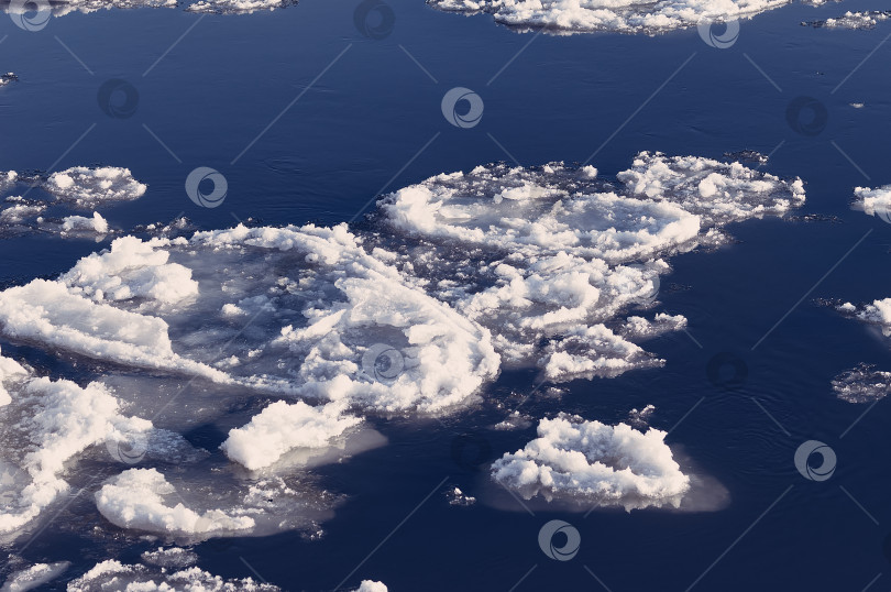 Скачать Ice floes float on the river. Seasonal ice drift. Reflection of the blue sky in the water. фотосток Ozero