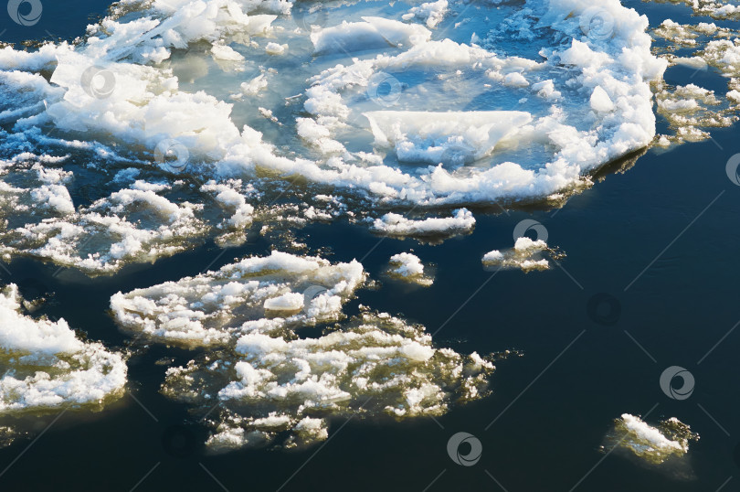Скачать Ice floes float on the river. Seasonal ice drift. Reflection of the blue sky in the water. Natural texture. фотосток Ozero