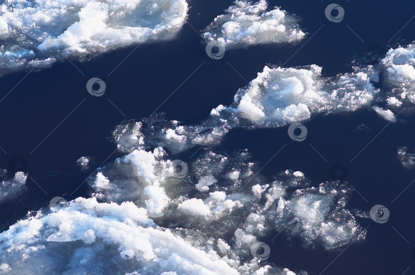 Скачать Ice floes float on the river. Seasonal ice drift. Reflection of the blue sky in the water. фотосток Ozero