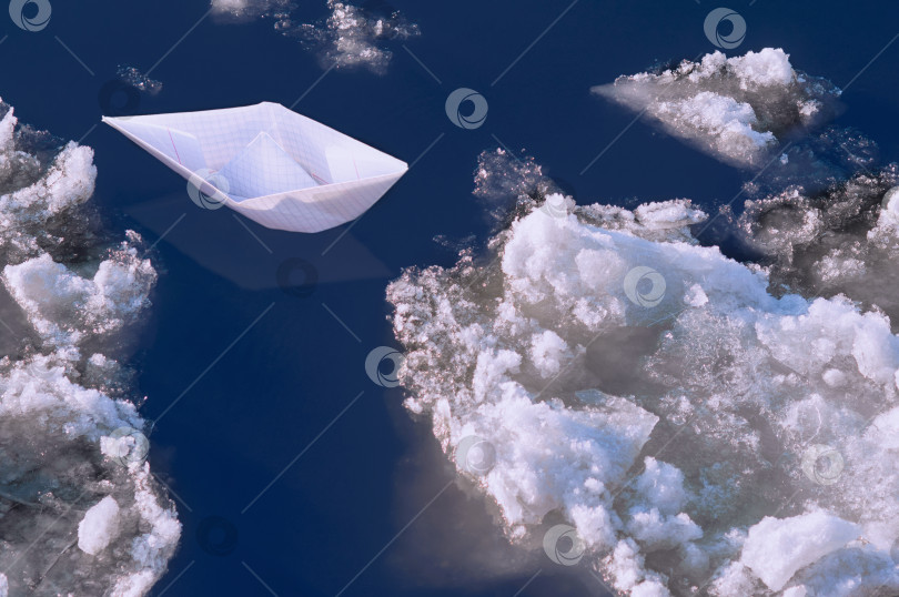 Скачать A paper boat floats among the ice floes in deep blue water. фотосток Ozero