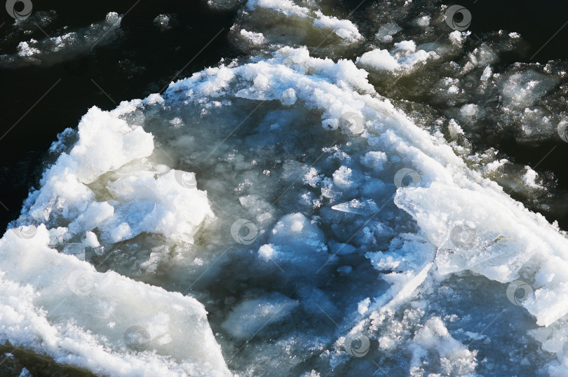 Скачать Ice floes float on the river. Seasonal ice drift. Reflection of the blue sky in the water. Natural texture. фотосток Ozero