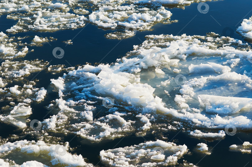 Скачать Ice floes float on the river. Seasonal ice drift. Reflection of the blue sky in the water. фотосток Ozero