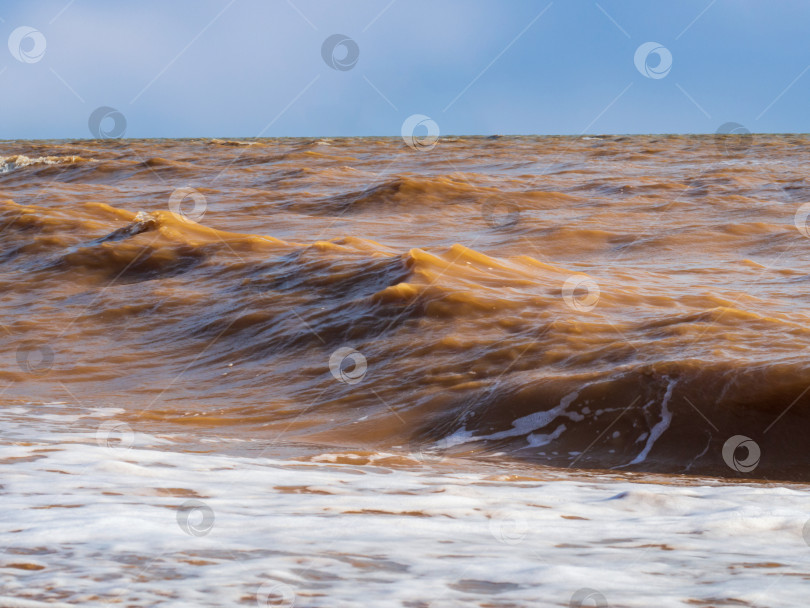 Скачать A stormy sea with muddy brown waves. The Sea of Azov during a storm, big waves against the sky фотосток Ozero