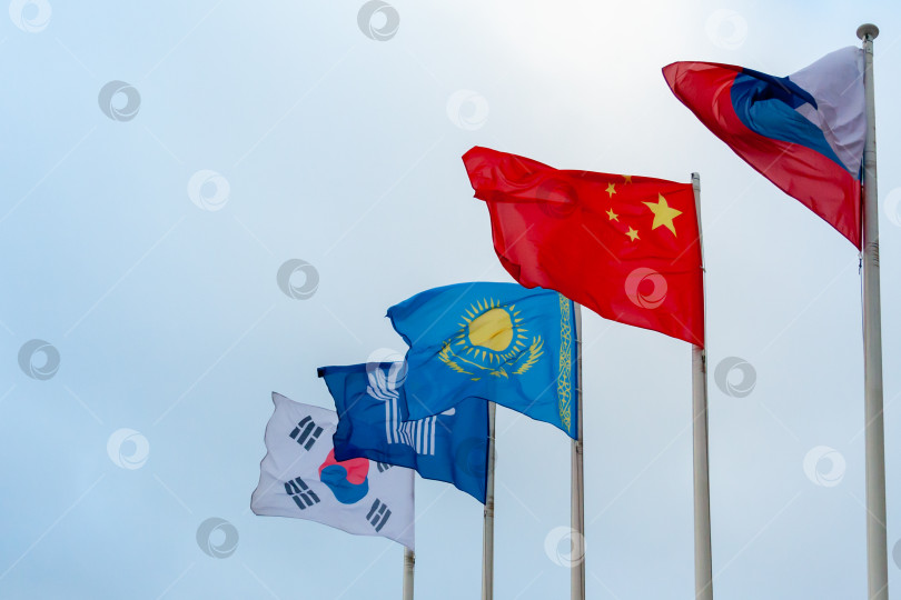 Скачать View on the flags of China, Kazakhstan, South Korea, Russia and Commonwealth of Independent States on the background of cloudy sky фотосток Ozero