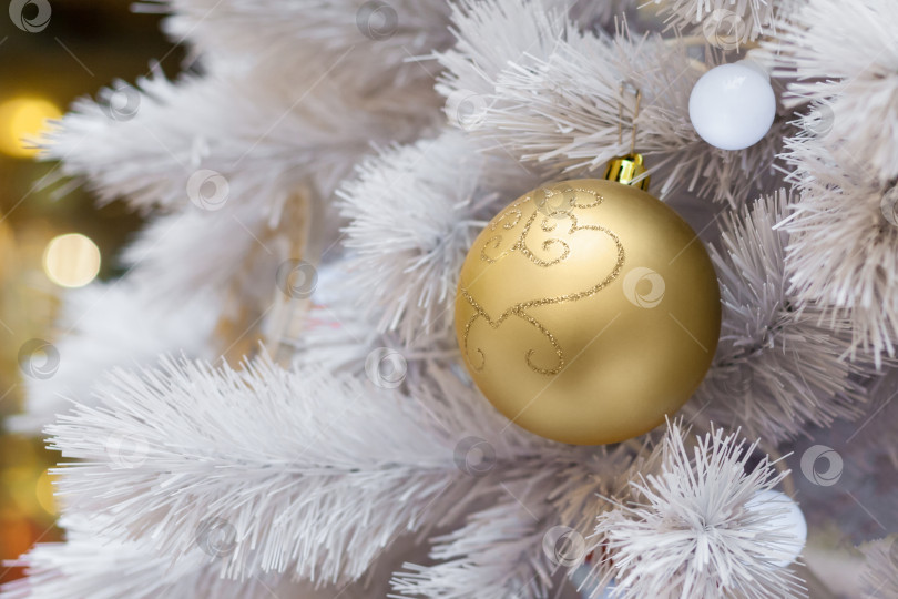 Скачать Close up view of a snow-covered artificial Christmas tree decorated with golden balls фотосток Ozero