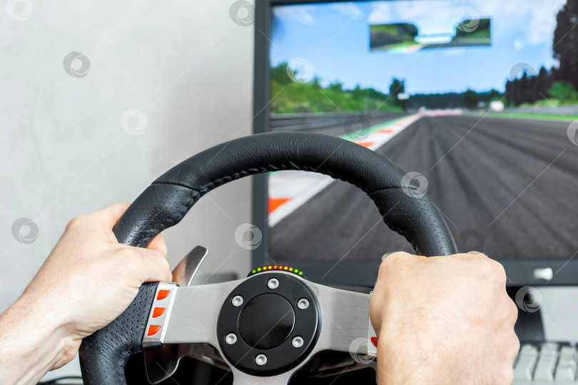 Скачать View on a man's hands playing a racing simulator on a steering wheel фотосток Ozero