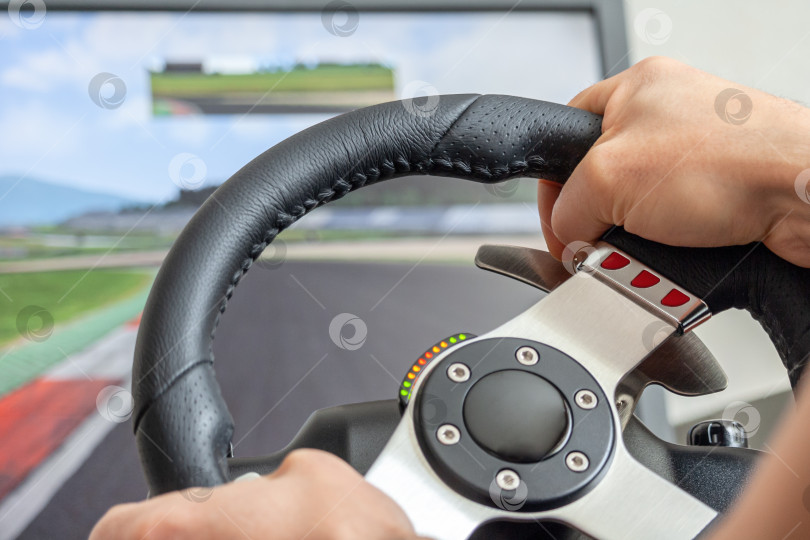 Скачать View on a man's hands playing a racing simulator on a steering wheel фотосток Ozero