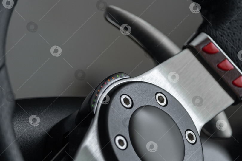 Скачать Close up view on a racing steering wheel with red buttons and metal gearshift paddles фотосток Ozero