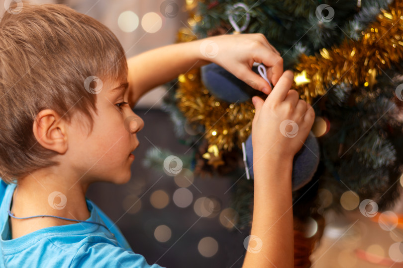 Скачать boy decorates Christmas tree with decorative holiday balls. Close-up фотосток Ozero