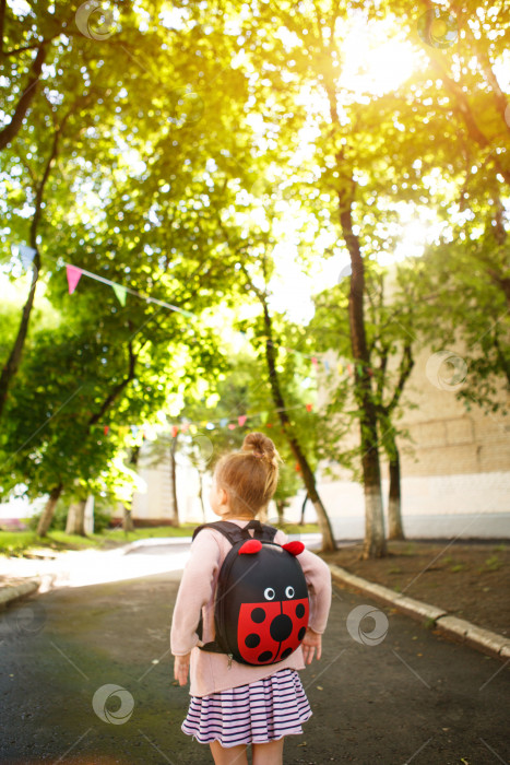 Скачать Маленькая девочка кавказской внешности в школьной форме с рюкзаком смотрит на дорогу в школьном дворе. Концепция возвращения в школу. Начальная школа, развивающие занятия для дошкольников. Пространство для текста фотосток Ozero