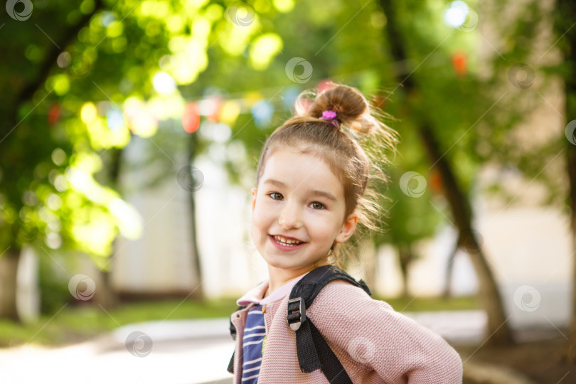 Скачать В кадр заглядывает маленькая девочка кавказской внешности в школьной форме с рюкзаком. Концепция возвращения в школу. Первое занятие, развивающие занятия для дошкольников. Пространство для текста фотосток Ozero