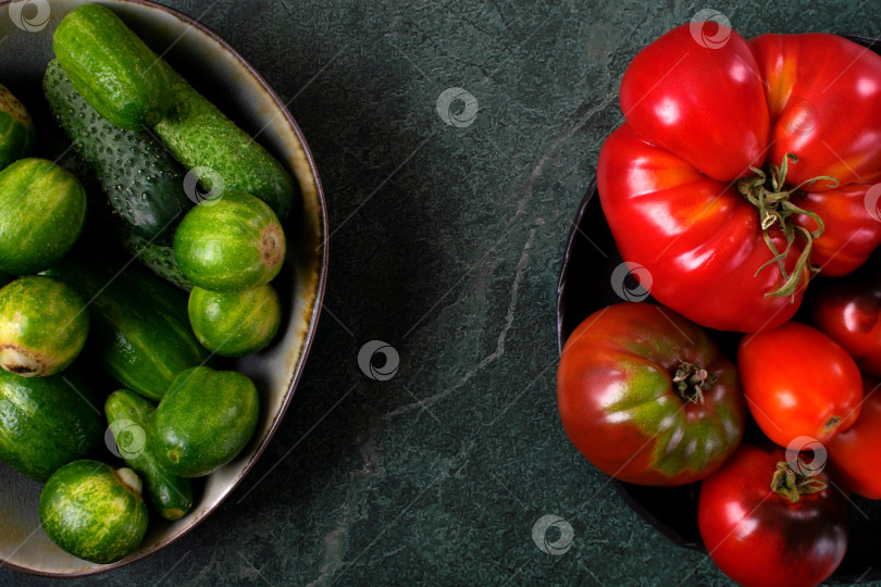 Скачать Assorted tomatoes and cucumbers of different colors and sizes on dark green table. Top view. фотосток Ozero