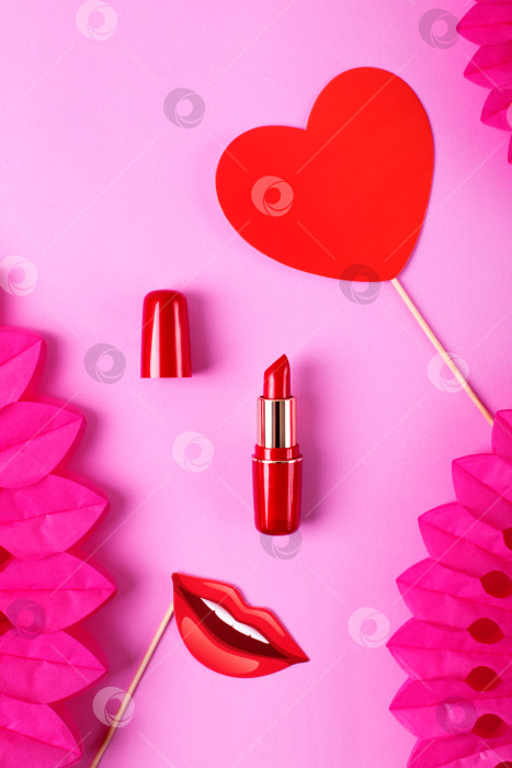 Скачать Red lipstick on pink background with party paper fans. фотосток Ozero