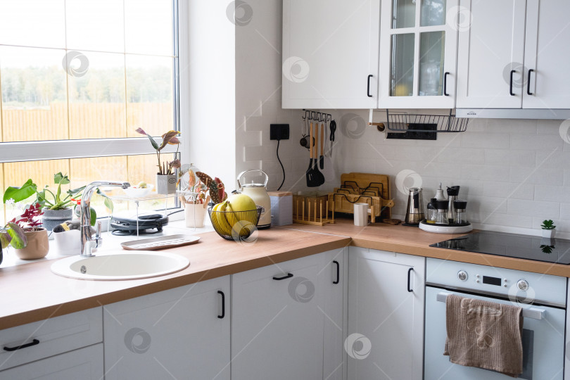 Скачать Белая уютная кухня в стиле Сканди лофт. Домашний интерьер, дизайн столовой, духовка, варочная поверхность, стол, кухонная мебель фотосток Ozero