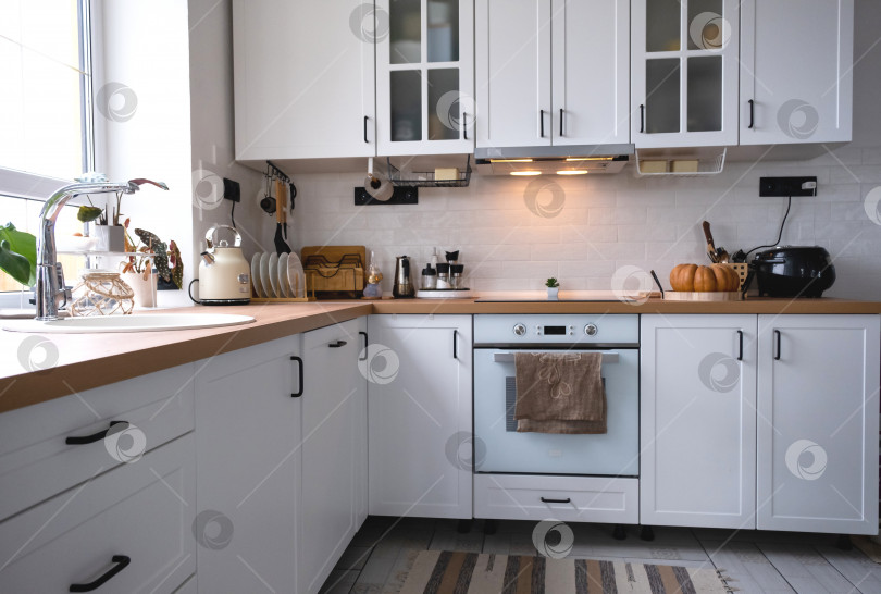 Скачать Белая уютная кухня в стиле Сканди лофт. Домашний интерьер, дизайн столовой, духовка, варочная панель, стол, кухонная мебель фотосток Ozero