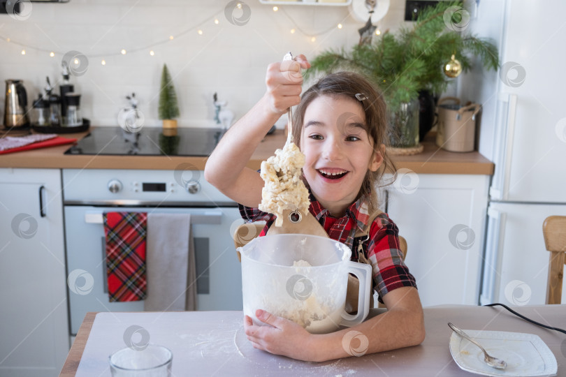 Скачать Дочь, обучающаяся готовить, помогает на белой кухне месить тесто в миске для пряников и печенья на Рождество и новый год. Выложите ингредиенты фотосток Ozero