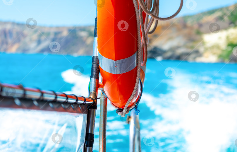 Скачать Оранжевый спасательный круг висит на поручнях быстроходного морского спасательного катера.Концепция летнего отдыха на море. фотосток Ozero