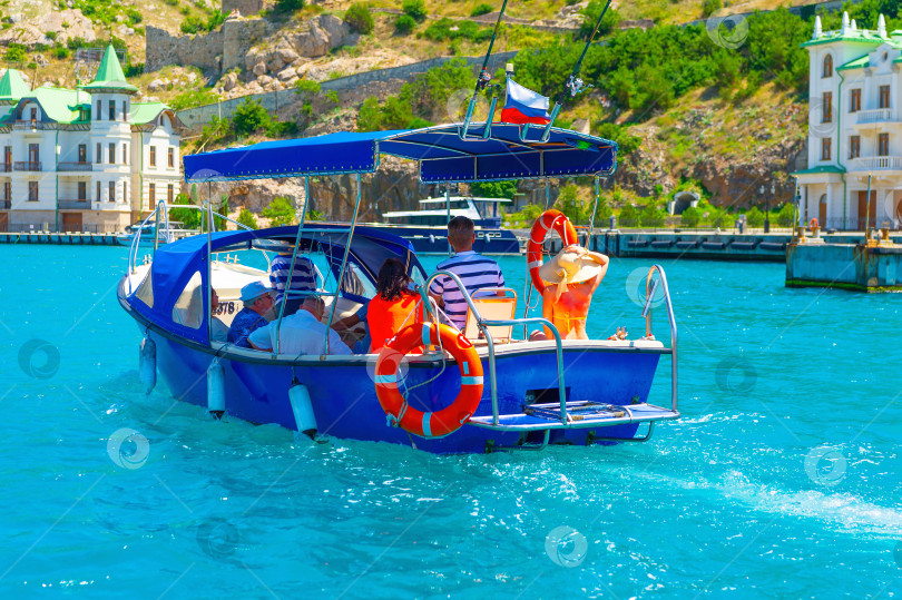 Скачать Крым, Балаклава, 16 июля 2022 года экскурсионный моторный катер, перевозящий туристов на прогулку по морю. фотосток Ozero