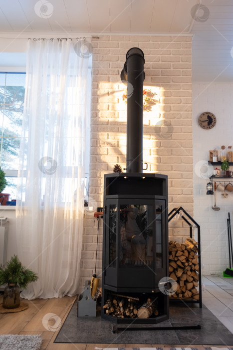 Скачать Черная печь, камин в интерьере дома в стиле лофт. Альтернативное экологичное отопление, теплая уютная комната дома, сжигание дров фотосток Ozero