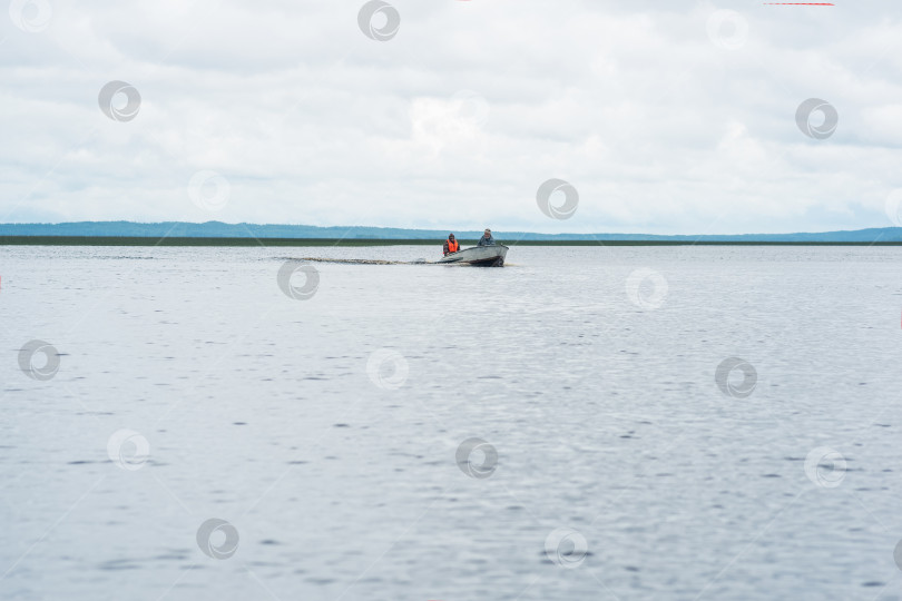 Скачать рыбаки на моторной лодке плывут по широкому озеру фотосток Ozero