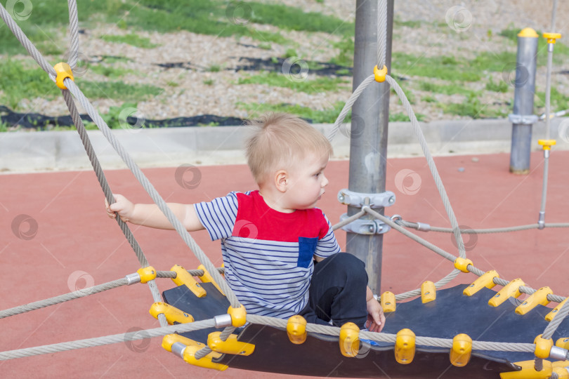 Скачать Маленький мальчик увлеченно играет на детской площадке. Успех, творческие идеи и спортивные концепции. Детская игровая площадка. фотосток Ozero
