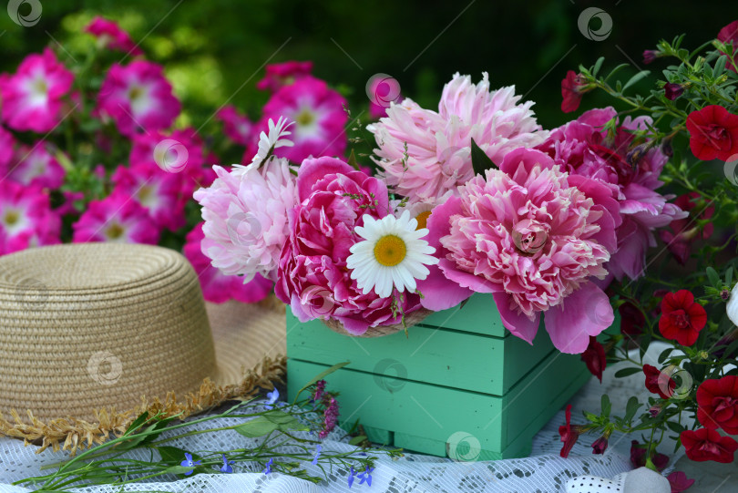 Скачать Beautiful still life with bunch of peony flowers and hat on the table in the garden. Romantic greeting card for birthday, Valentines, Mothers Day concept. Summer background with vintage objects фотосток Ozero