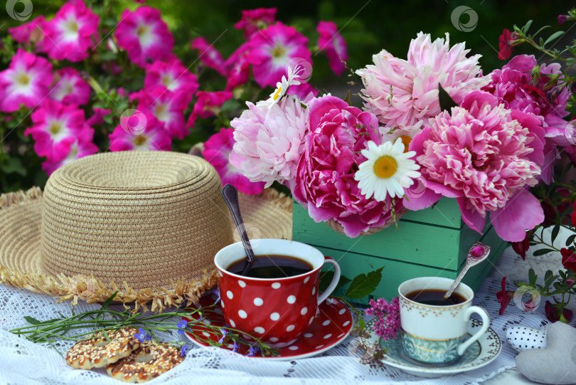 Скачать Beautiful still life with peony flowers bunch, tea cup and hat on the table. Romantic greeting card for birthday, Valentines, Mothers Day concept. Summer background with vintage objects фотосток Ozero