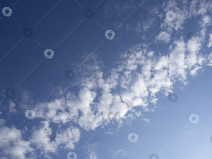 Скачать Голубое небо с облаками. Естественный фон неба. Верхний левый угол темно-синий, нижний правый угол светло-голубой, освещенный солнцем, в центре по диагонали белые пушистые облака. фотосток Ozero