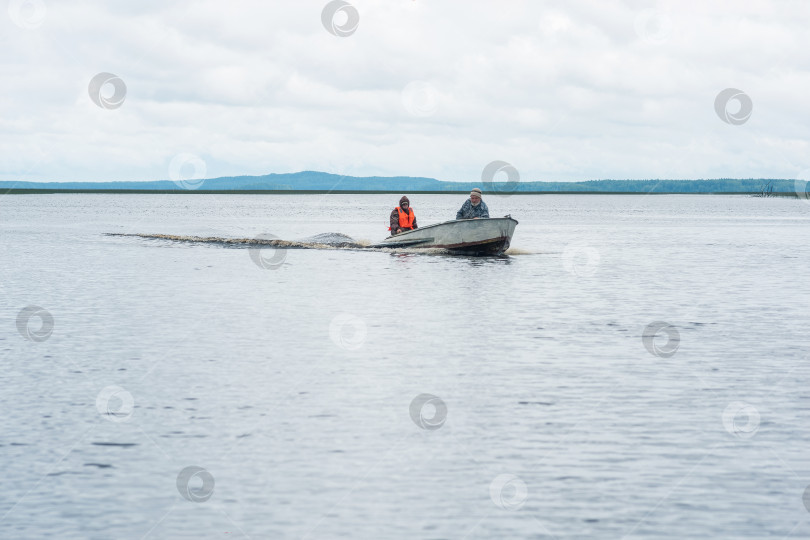 Скачать рыбаки на моторной лодке плывут по широкому озеру фотосток Ozero