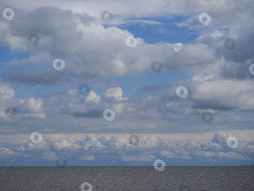 Скачать Белые кучевые облака в голубом небе над морским пейзажем, большое количество облаков над панорамой океанской воды, пасмурная погода фотосток Ozero