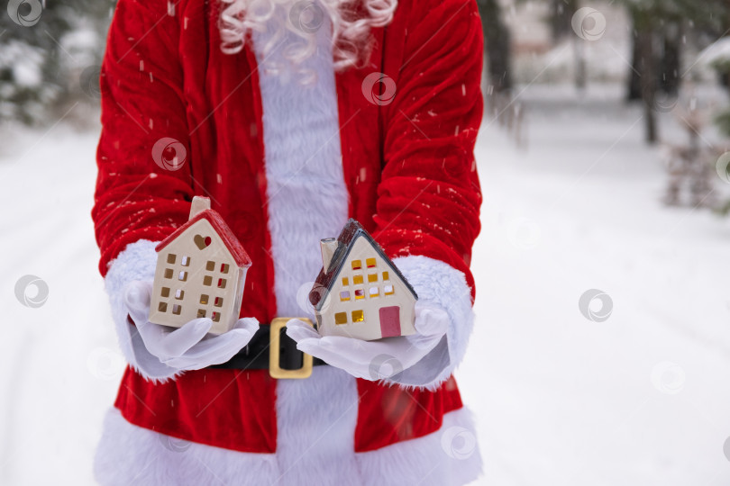 Скачать Ключ от дома с брелком коттедж в руках Санта-Клауса на открытом воздухе в снегу. Сделки с недвижимостью, покупка, строительство, переезд, ипотека. Уютный дом. Счастливого Рождества, новогоднего мероприятия по бронированию билетов и зала фотосток Ozero