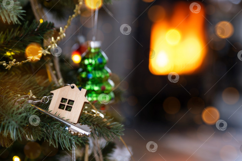 Скачать Ключ от дома с брелоком висит на рождественской елке. Подарок на Новый год, Рождество. Строительство, дизайн, проектирование, переезд в новый дом, ипотека, аренда и покупка недвижимости. Пространство для копирования фотосток Ozero