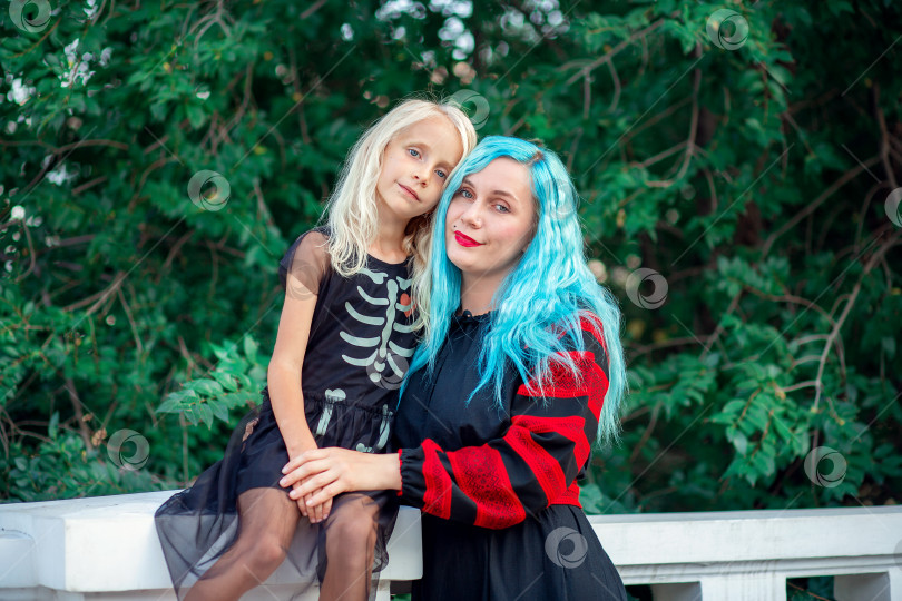 Скачать Молодая женщина с голубыми волосами обнимает свою дочь в платье с рисунком скелета фотосток Ozero