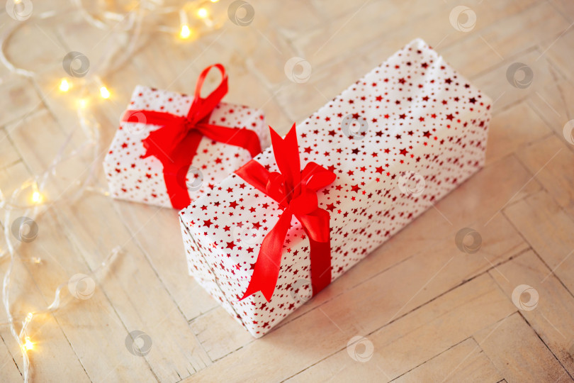 Скачать Две коробки в подарочной упаковке лежат на полу, перевязанные красной лентой фотосток Ozero