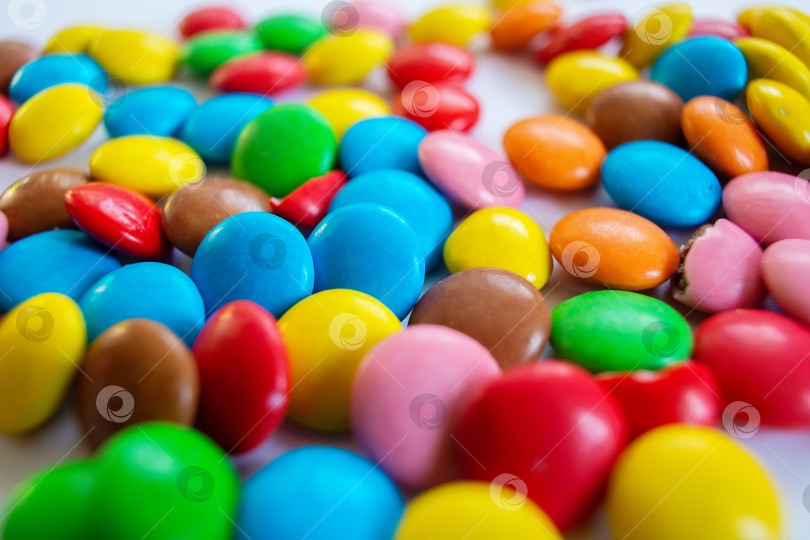 Скачать На столе разбросано множество разноцветных маленьких круглых конфет. фотосток Ozero