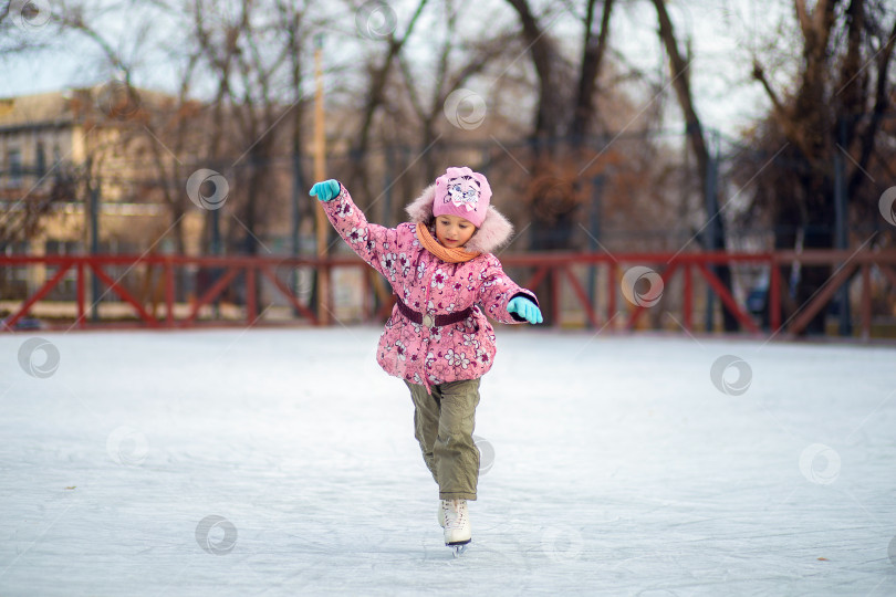 Скачать Девочка учится кататься на коньках на уличном катке зимой фотосток Ozero