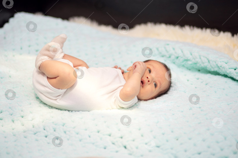 Скачать Маленький новорожденный малыш в белом боди лежит дома на диване фотосток Ozero