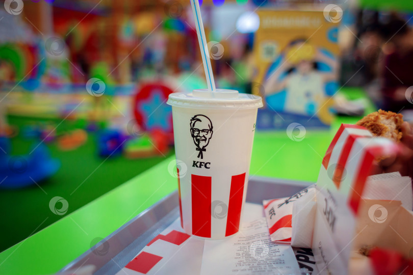 Скачать Волгоград, Россия, 13.10.2019: Бокал с напитком на подносе с брендом сети быстрого питания KFC фотосток Ozero