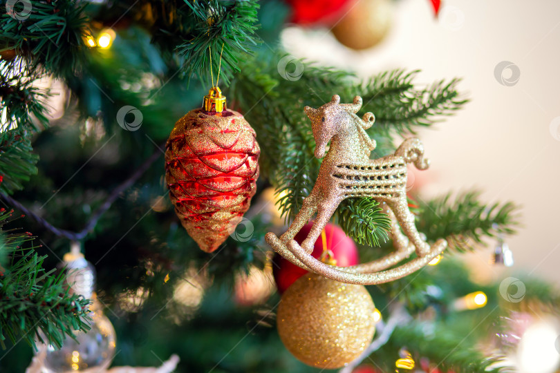 Скачать Украшение рождественской елки. Стеклянная золотая шишка и лошадь на ветке крупным планом фотосток Ozero