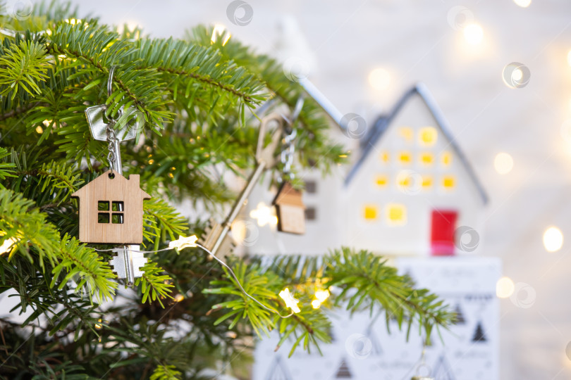 Скачать Ключ от дома с брелоком висит на рождественской елке. Подарок на Новый год, Рождество. Строительство, дизайн, проектирование, переезд в новый дом, ипотека, аренда и покупка недвижимости. Пространство для копирования фотосток Ozero