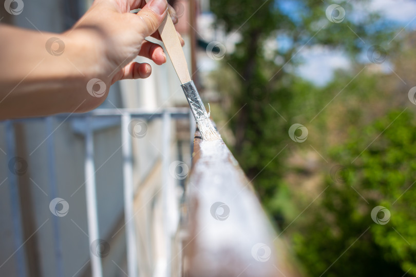Скачать Процесс покраски ржавых облупившихся прутьев на заборе. Мужчина рисует кистью забор, рука крупным планом фотосток Ozero