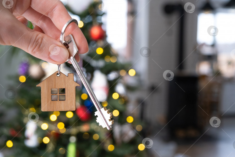 Скачать Ключ от дома в руке на фоне рождественской елки. Подарок на Новый год, Рождество. Строительство, дизайн, проект, переезд в новый дом, ипотека, аренда и покупка недвижимости. Пространство для копирования фотосток Ozero