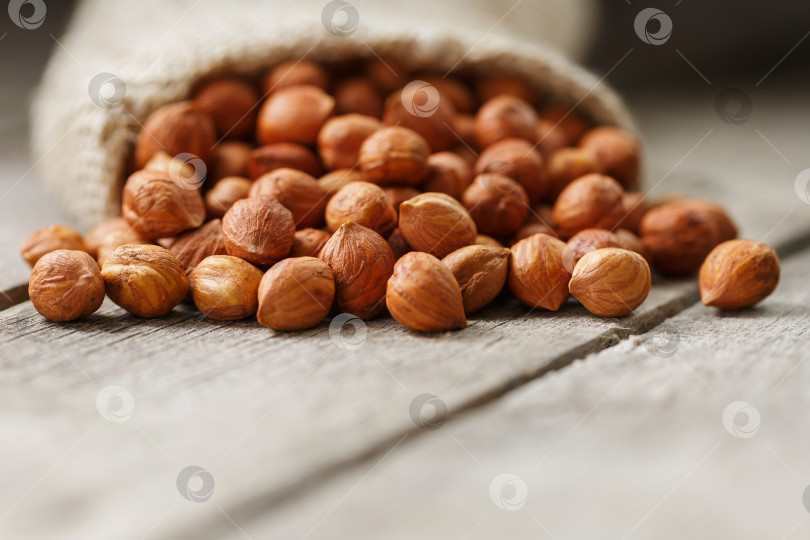 Скачать Измельченные лесные орехи в мешковине на сером деревянном столе. Органический свежий урожай фотосток Ozero