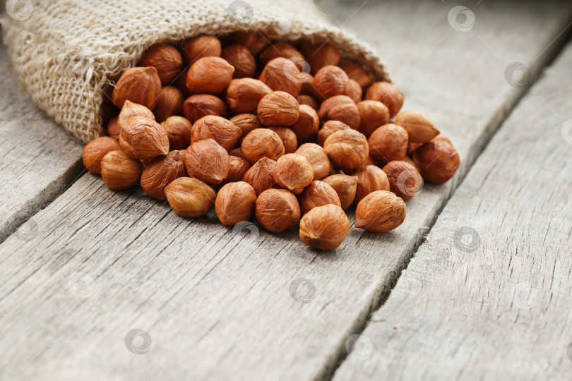 Скачать Измельченные лесные орехи в мешковине на сером деревянном столе. Органический свежий урожай фотосток Ozero