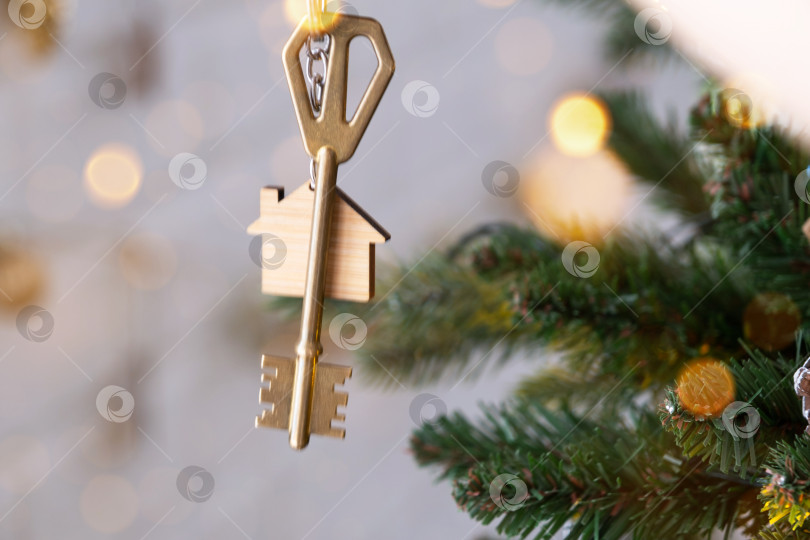 Скачать Ключ от дома с брелоком висит на рождественской елке. Подарок на Новый год, Рождество. Строительство, дизайн, проект, переезд в новый дом, ипотека, аренда и покупка недвижимости. Пространство для копирования фотосток Ozero