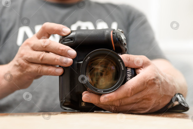 Скачать Россия, Санкт-Петербург, август 2023 года: Мужские руки держат камеру Nikon 4D крупным планом фотосток Ozero
