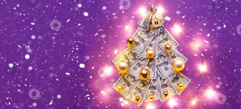Скачать Рождественская елка из 100-долларовых купюр на фиолетовом фоне с копировальным пространством и ключом от дома. Рождественский декор финансов, сбережений, богатства, расходов в новом году. Недвижимость, жилье, ипотека, переезд фотосток Ozero