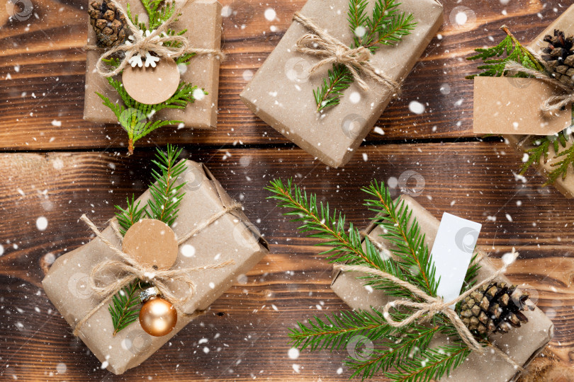 Скачать Упакуйте подарок на Рождество и новый год из экологически чистых материалов: крафт-бумаги, живых еловых веток, шишек, шпагата, снега. Бирки с макетом, натуральный декор, ручная работа, сделай сам. Праздничное настроение. Категорически, предыстория фотосток Ozero