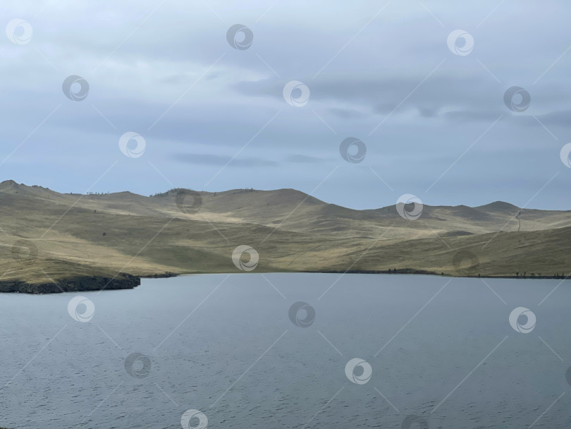 Скачать Озеро Байкал ранним утром, туманная дымка над водой. Мрачный суровый пейзаж фотосток Ozero