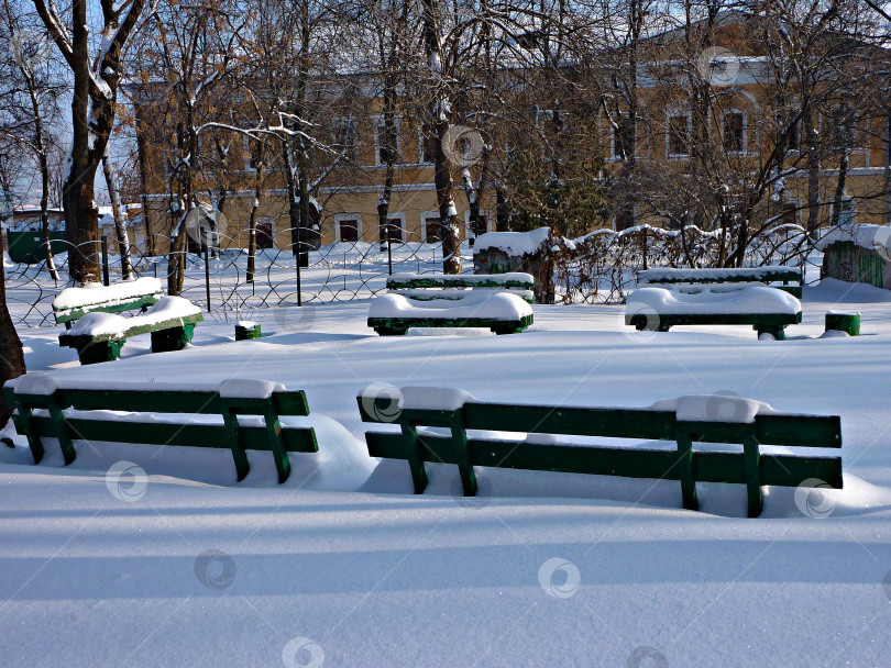 Скачать Заснеженные скамейки в городском сквере фотосток Ozero